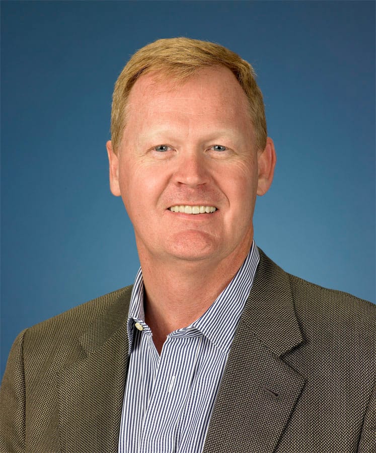 Mark chapman, caucasian male executive smiling in a suit